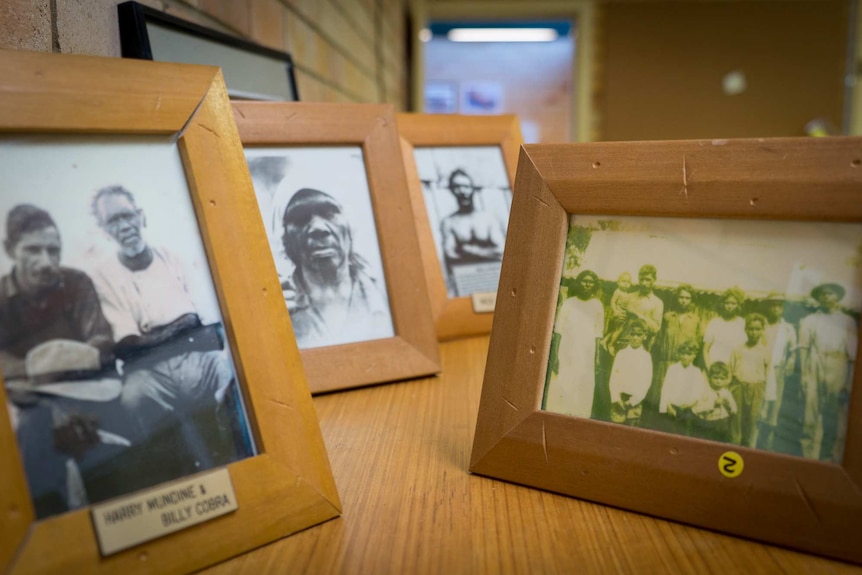 Photographs in frames on a table in a school building hallway of Indigenous ancestors