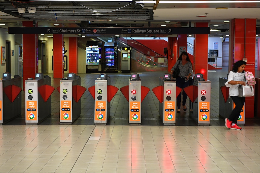 people walking through turnstile at a train station