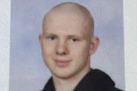 A person with a shaved head and in a hooded top.