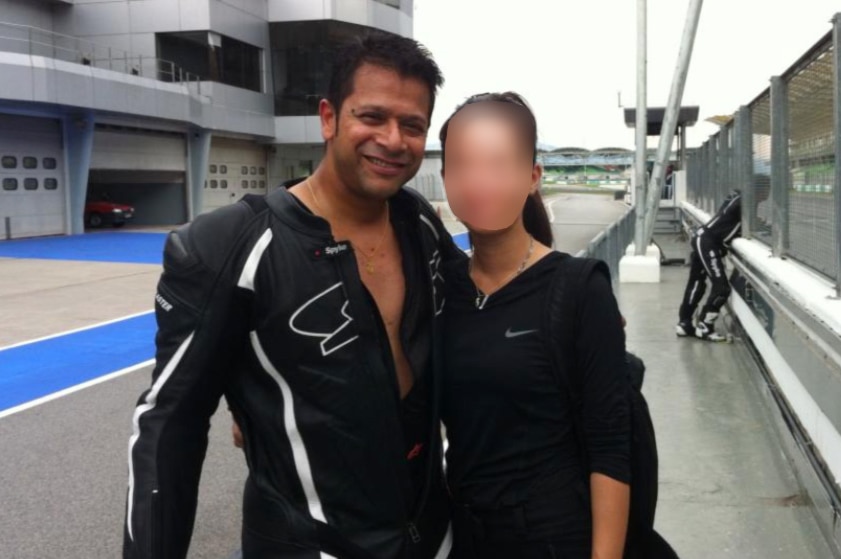 Alfred Gerard Eravelly stands wearing racing leathers next to a girl whose face is blurred.