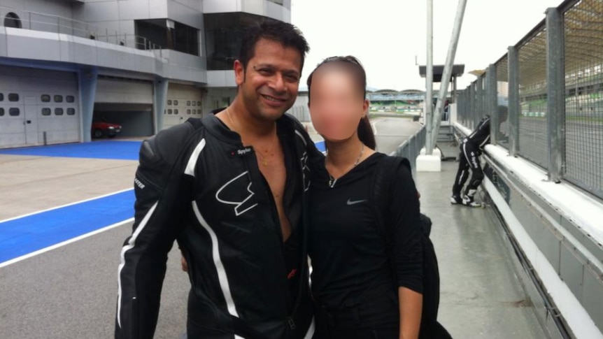 Alfred Gerard Eravelly stands wearing racing leathers next to a girl whose face is blurred.