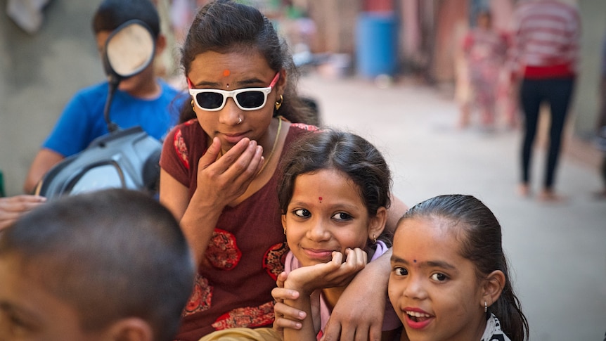 Three girls pose in this street shot from the Kanjabhat community in Pune, India.