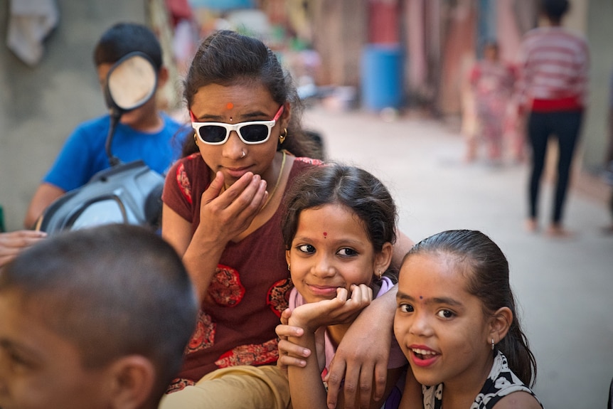 Three girls pose in this street shot from the Kanjabhat community in Pune, India.