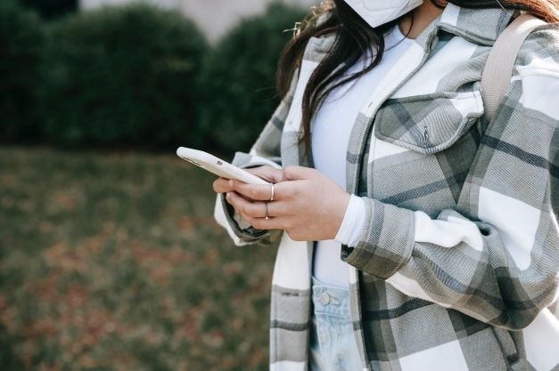 Una mujer se encuentra en un campo y mira la pantalla de su teléfono inteligente.