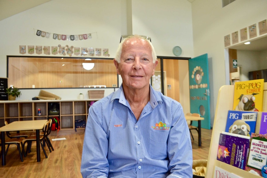 A man in a blue shirt sits in a library