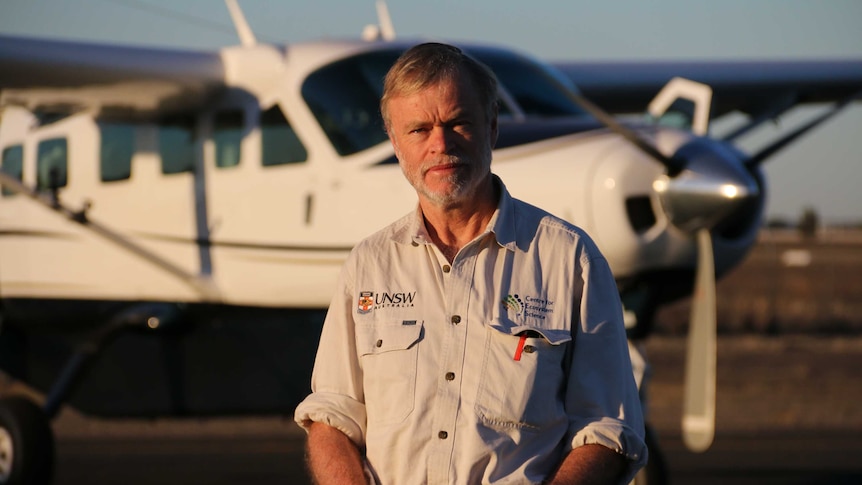 A man stands in front of a light plane