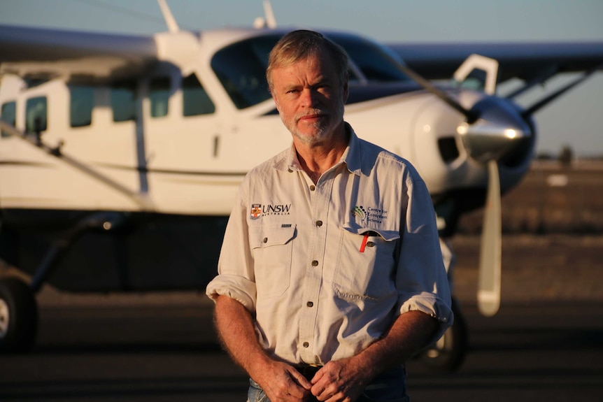 A man stands in front of a light plane