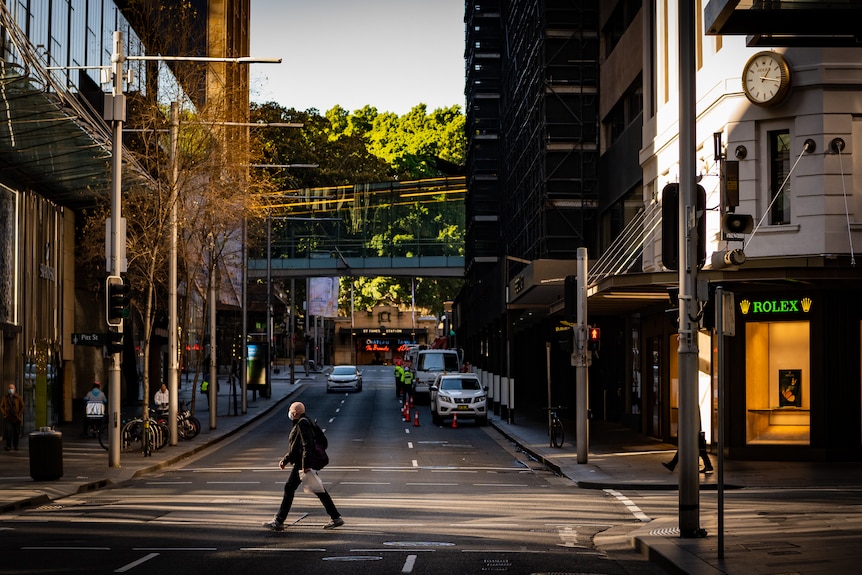 a man in a mask crossing a mostly empty road