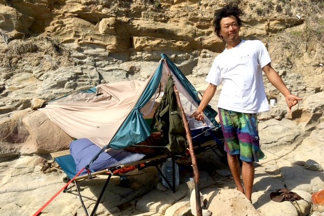 Toru standing in front of a tent on the rocks near Bulli.