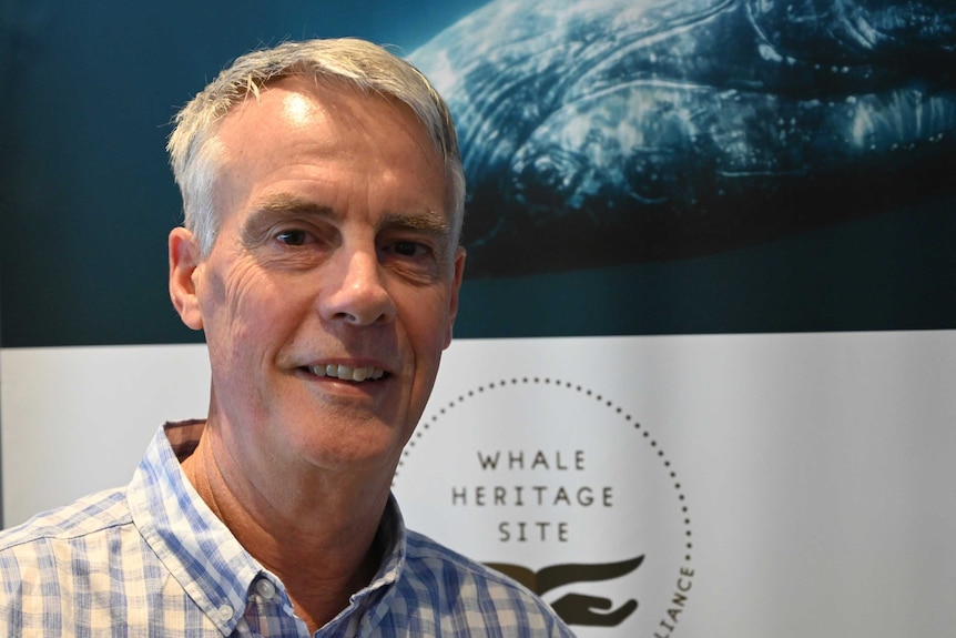 Fraser Coast Tourism general manager Martin Simons stands smiling infront of a whale sign.