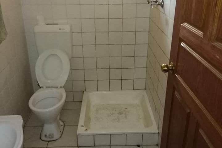 An unclean looking bathroom with the toilet right next to the shower.