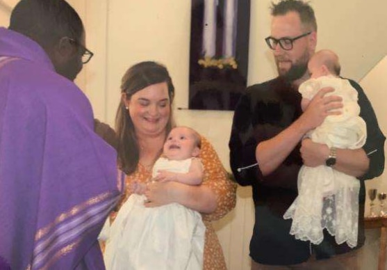 Twins being christened and held in arms of their parents