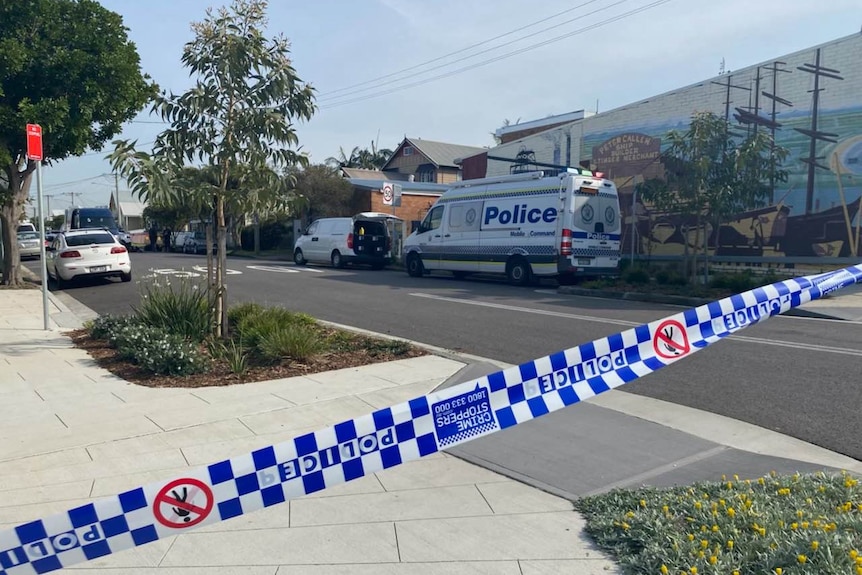 A police vehicle in a street and police tape.