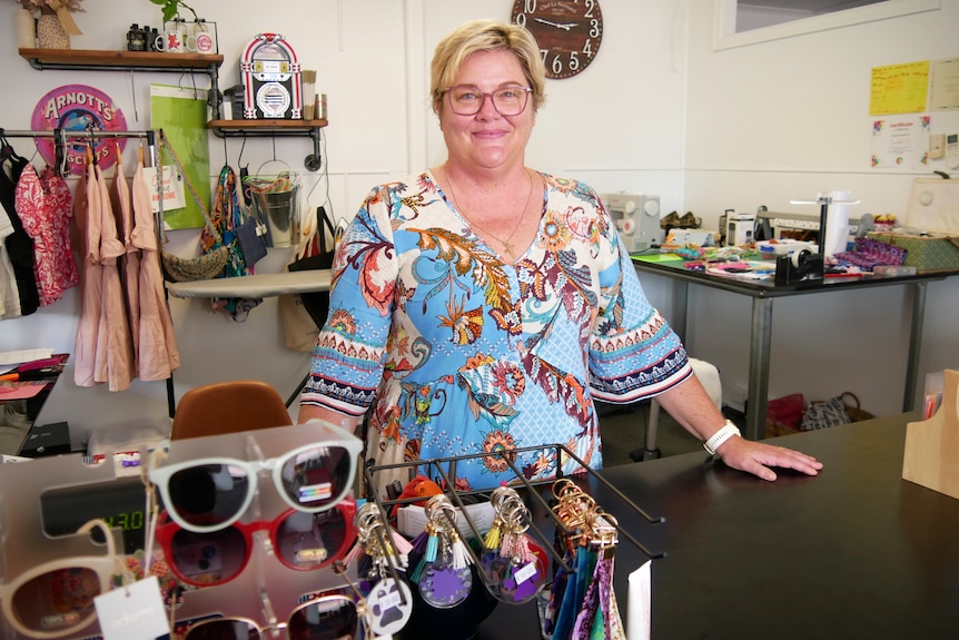 A woman stands behind the counter of a retail store 