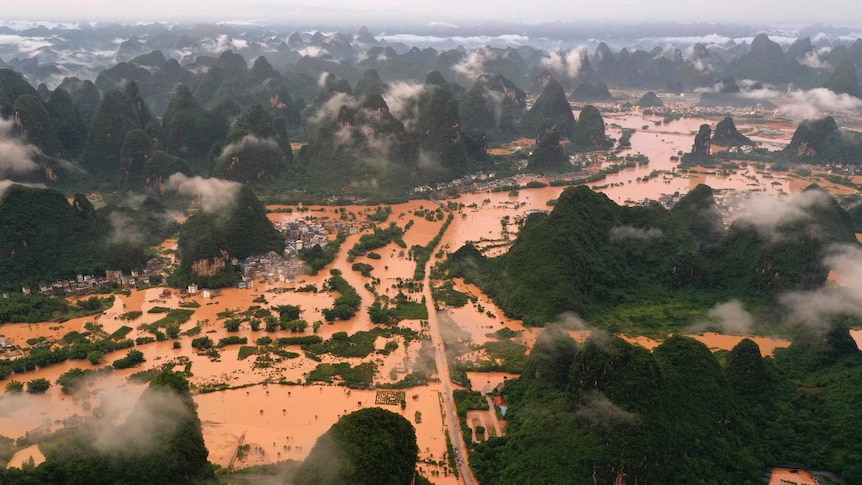 An aerial view of a flooded area with vegetation-covered karst mountains rising out of it