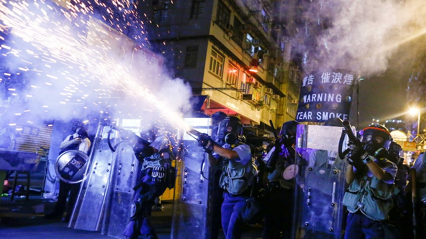 Hong Police shooting tear gas canister in a city street at night