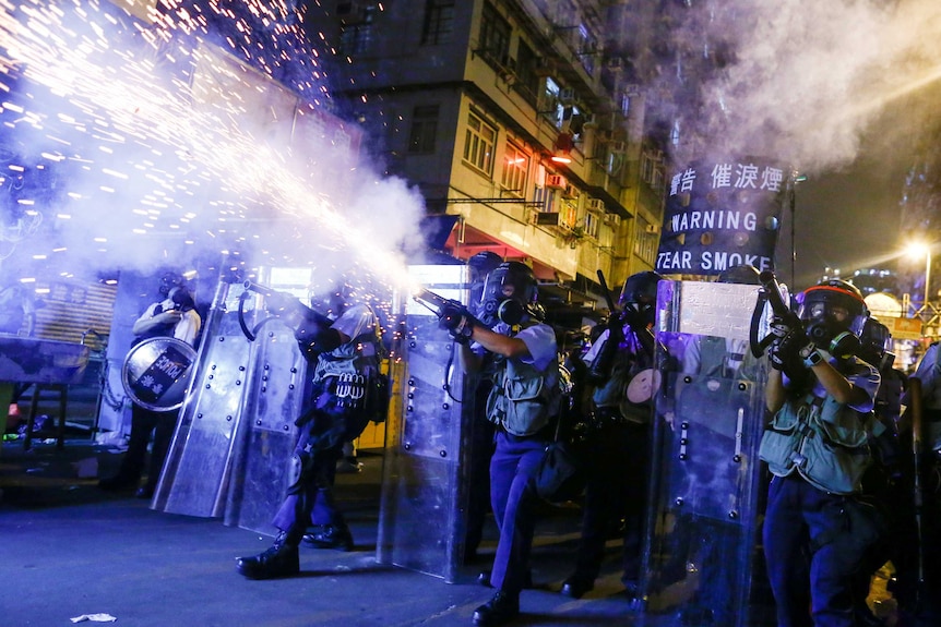 Hong Police shooting tear gas canister in a city street at night