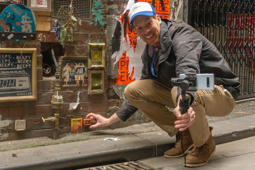 A man holding a camera in front of graffiti