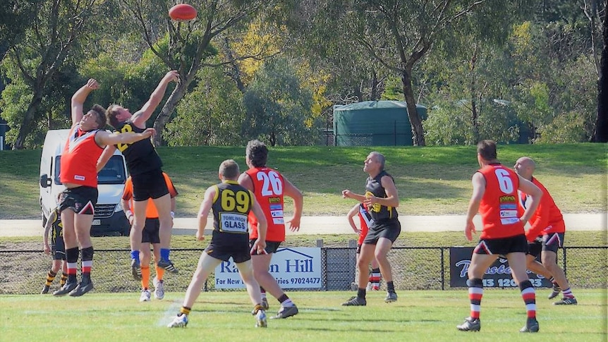 Action at a veterans AFL game in Victoria. The ball is in the air and several players are jostling