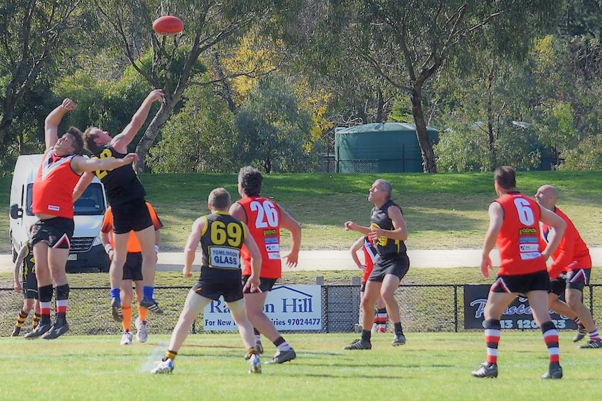 Action at a veterans AFL game in Victoria. The ball is in the air and several players are jostling