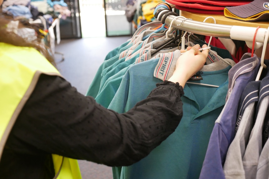 A woman hangs a polo shirt onto a railing