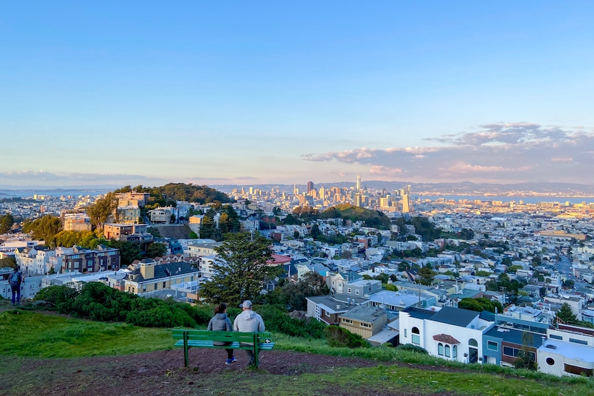 Two people on a park bench looking out at San Francisco's skyline