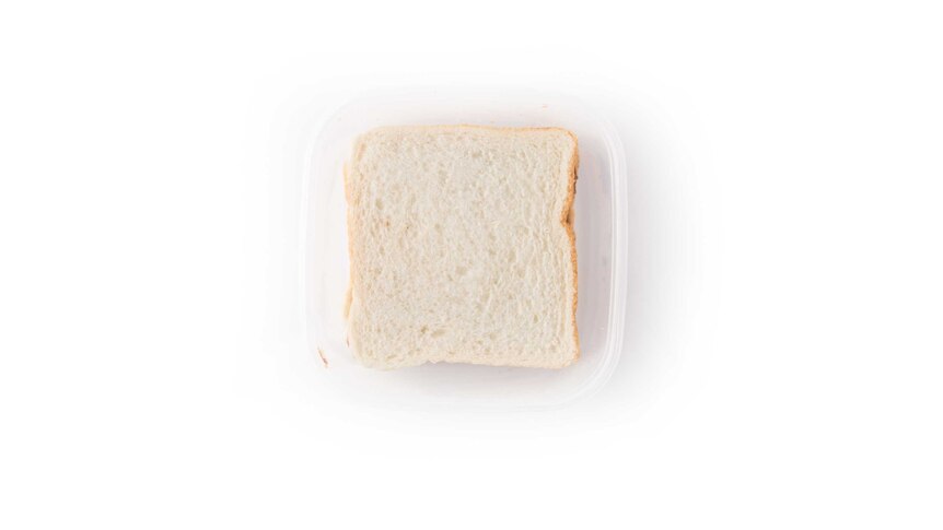 A white bread Nutella sandwich in a clear plastic lunch box on a white background.