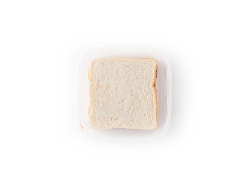 A white bread Nutella sandwich in a clear plastic lunch box on a white background.