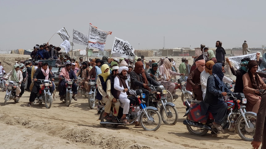 Supporters of the Taliban ride motorbikes and carry their signature white flags 