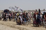 Supporters of the Taliban ride motorbikes and carry their signature white flags 