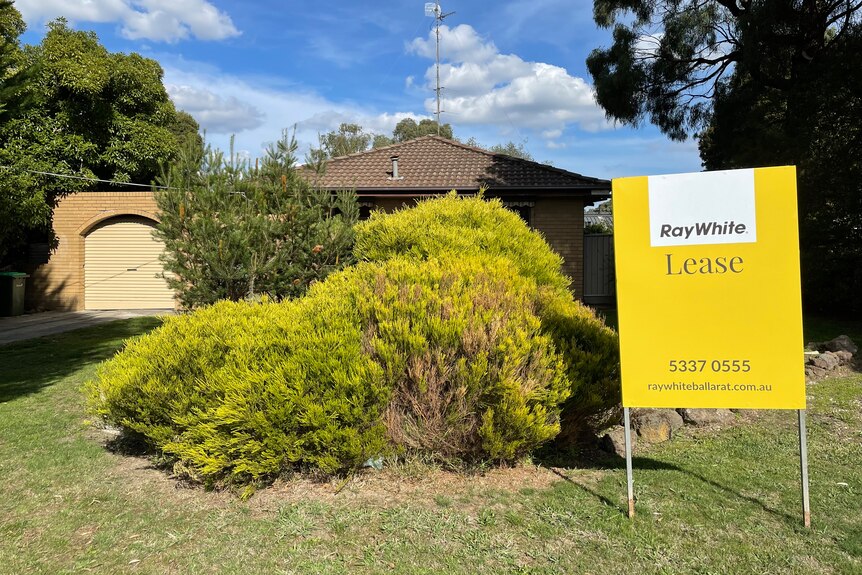 A house with a front garden and a yellow lease sign. 