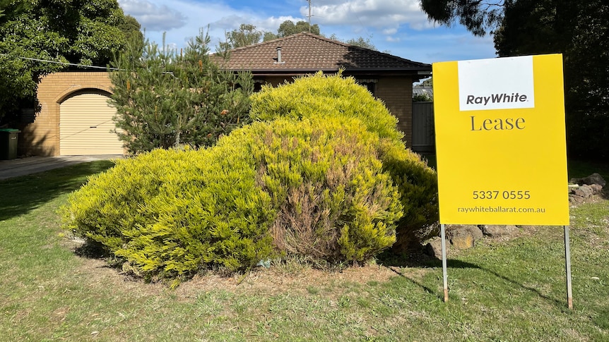 A house with a front garden and a yellow lease sign. 