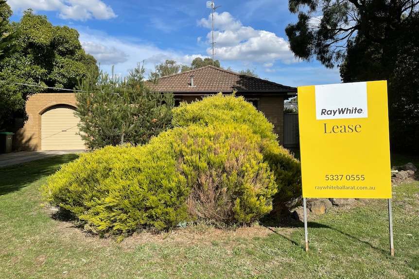 A house with a front garden and a yellow lease sign. 