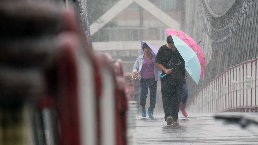 Local residents walk on a suspension bridge in Bitan in the New Taipei City.