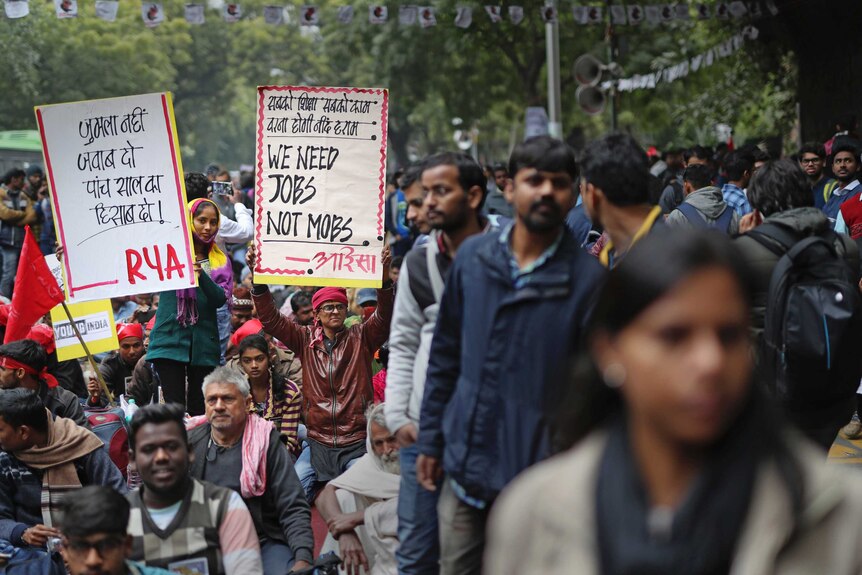 Several people hold placards among a crowded protest in New Delhi, India.