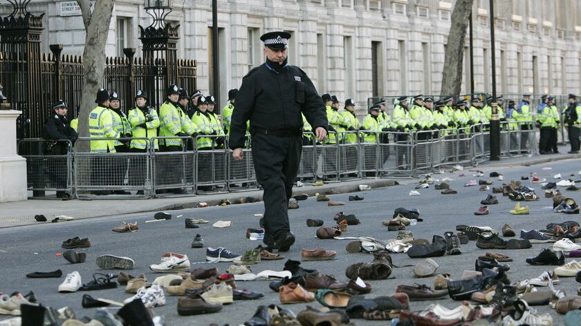A police officer walks through a sea of shoes, thrown by protesters, near the residence of British PM Gordon Brown.