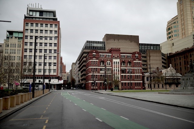 An empty city street with mid-20th century buildings behind