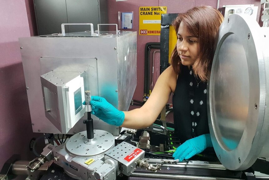 Carla Raymond carefully places a lead scroll into ANSTO's neutron imaging instrument named Dingo.