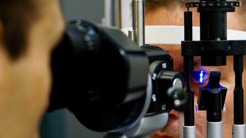 A close up photo of an ophthalmologist examining a man's eyes.
