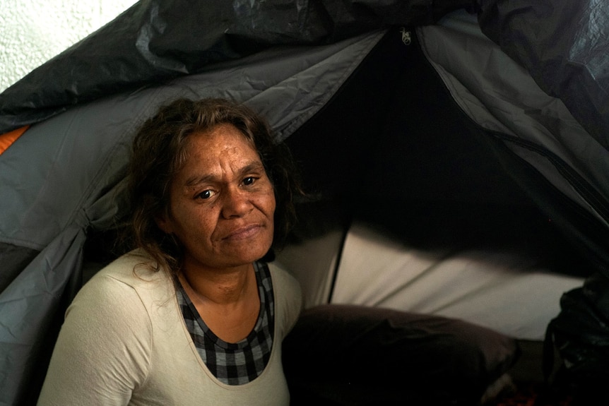 A woman sits in front of a tent.