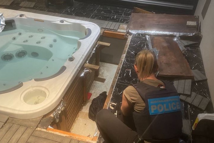A police officer inspects a spa that has been pulled apart.
