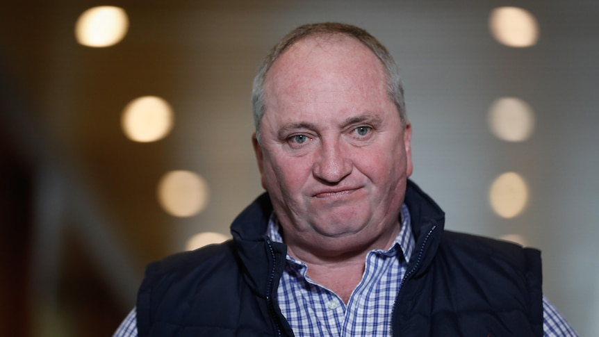 Tight shot of Joyce looking cranky. He's wearing a checkered shirt and dark puffer vest.