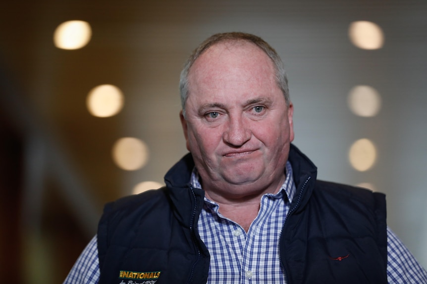 Tight shot of Joyce looking cranky. He's wearing a checkered shirt and dark puffer vest.