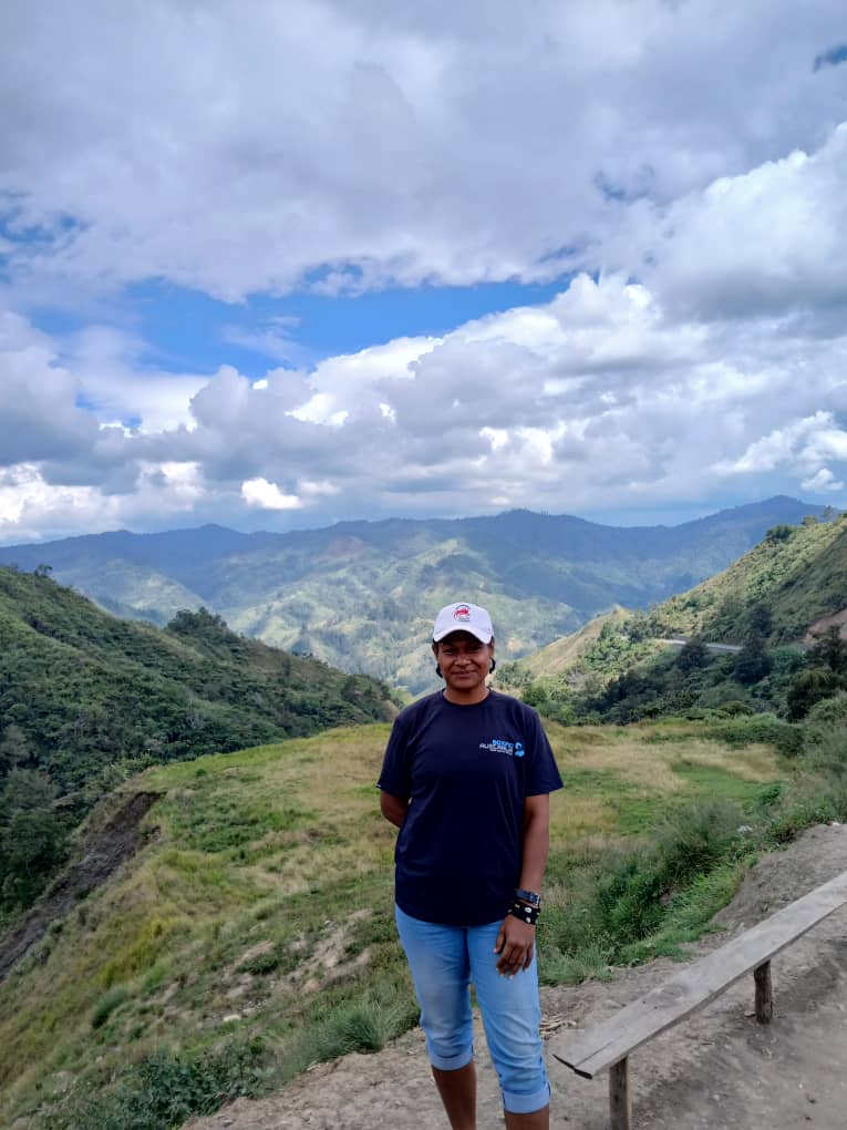 Woman stands at a mountain view lookout in Papua New Guinea.