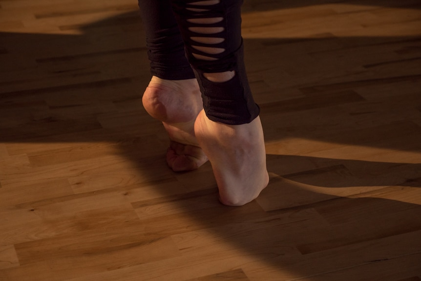 Fiona stretches her feet, by folding her toes under them, before practice.