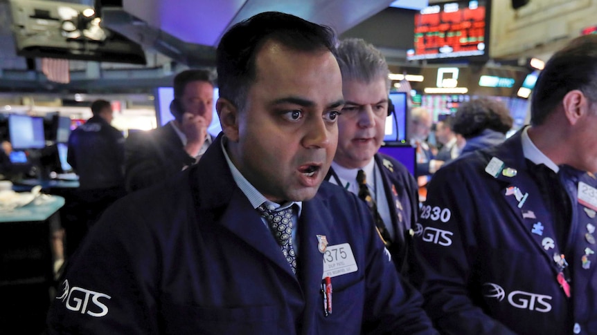 A Wall Street trader looks at a screen at the New York Stock Exchange with his mouth agape.
