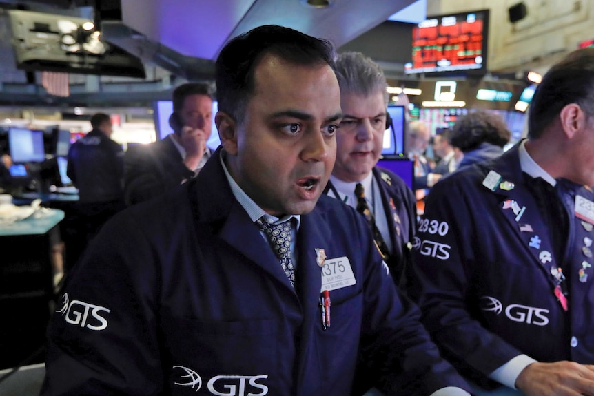 A Wall Street trader looks at a screen at the New York Stock Exchange with his mouth agape.