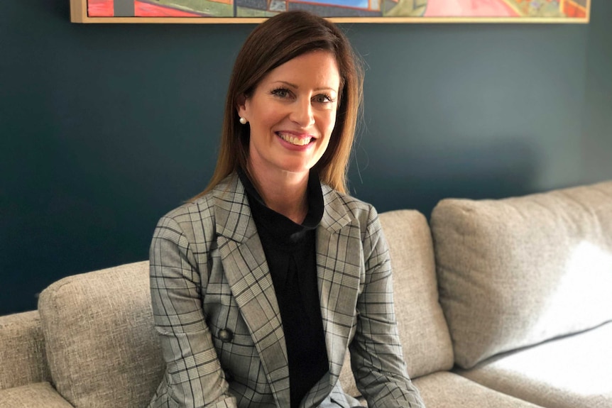 Cate Bakos sits on a sofa.