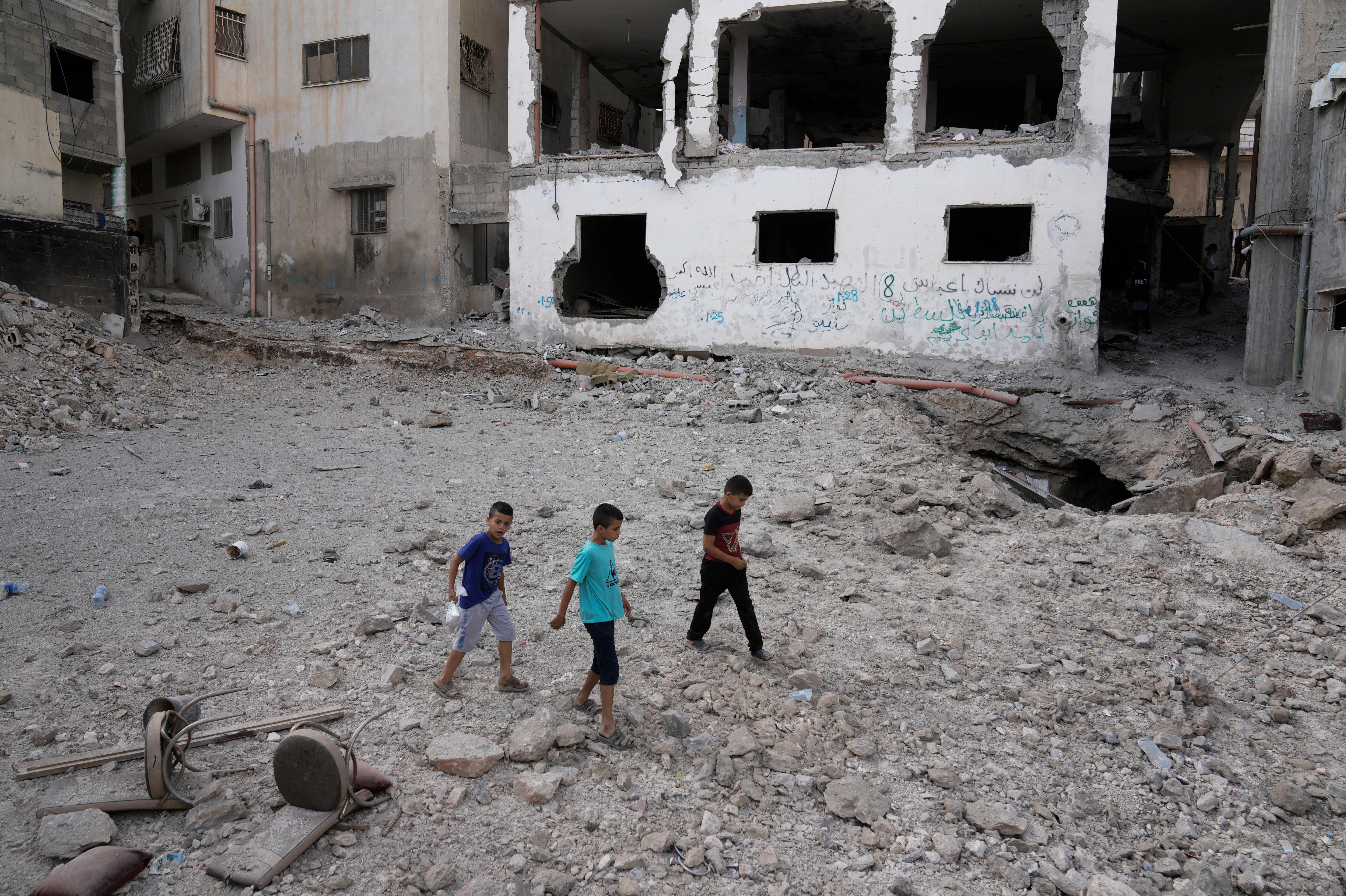 Three children walk on rubble.