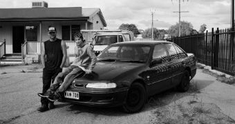Two men lean against a Holden Commodore.